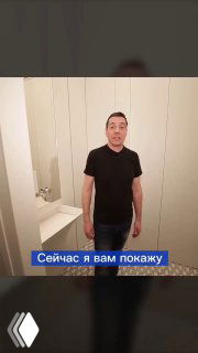 Мужчина стоит перед встроенными дверцами шкафа в интерьере — пример решения, где за дверцами можно скрыть стиральную и сушильную машины и хозблок.