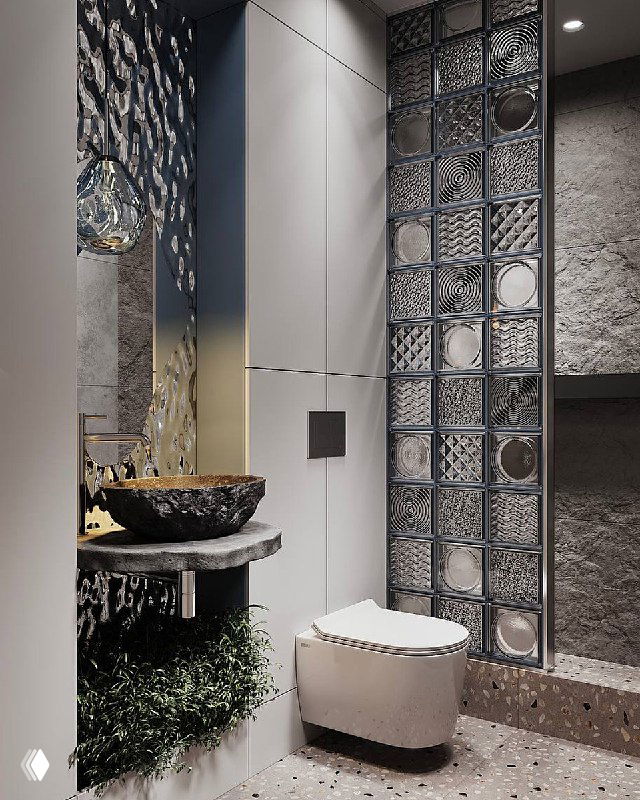 Интерьер санузла с компактной зоной умывания: переливающееся цветное стекло, светильник Wooddi, стеклоблоки и фактурный керамогранит, создающие ощущение оазиса.