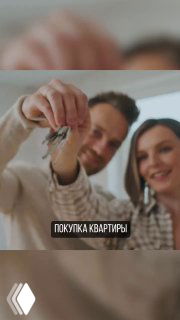 Пара держит ключи от квартиры на фоне размытых элементов интерьера; изображение иллюстрирует тему покупки квартиры, ремонта и начала дизайнерского проекта.