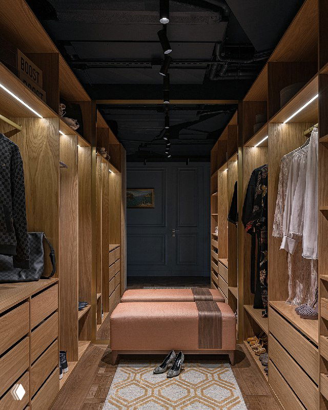 Коридор гардеробной с медовыми деревянными шкафами по бокам, банкеткой в центре, чёрным необшитым потолком, узорчатым ковриком и приглушенным светом.