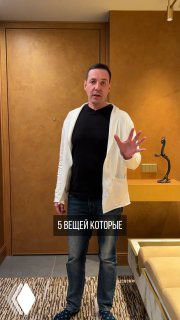 Мужчина в светлой кофте стоит в оформленной прихожей рядом с тумбой и декоративной скульптурой; кадр иллюстрирует идею зоны входа.