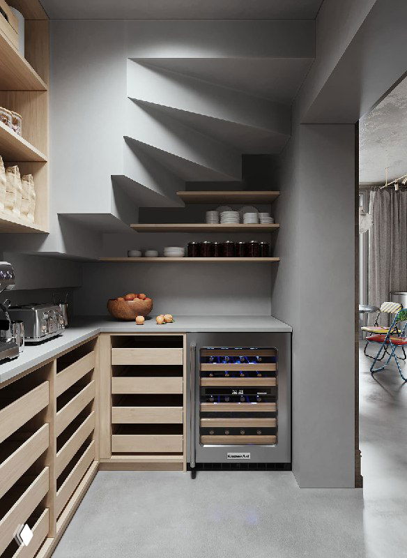 Вид уголка кладовой: рабочая столешница, полки с банками и бутылками, встраиваемый винный шкаф и места для сезонных запасов и техники.