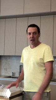 Мужчина в жёлтой футболке на фоне компактной кухни: фасады шкафов, столешница и фрагмент компактного острова-решения проекта