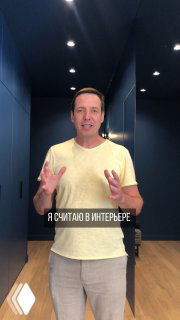 Человек в светлой футболке на фоне тёмно-синего минималистичного интерьера; скрытый вдоль стены шкаф, банкетка и светильники как фокус композиции.