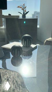 Бекстейдж со съёмок в Башне Исеть: отражающий журнальный стол с двумя декоративными сферами, вазой и видом из окна на город.