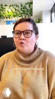 Крупный план авторки — женщина в очках и тёплом свитере на фоне зелёной интерьерной стены и окна; скриншот из видео процесса обсуждения планировки.