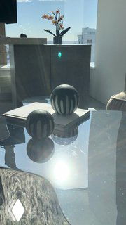 Отражающий стеклянный стол с декоративными круглыми объектами и вазой на фоне окна с видом из интерьера проекта в Башне Исеть