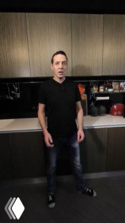 Мужчина в современной кухне у встроенных шкафов и столешницы, демонстрирующий вариант размещения микроволновки за фасадом.