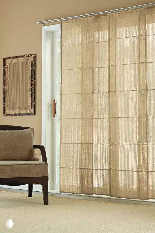 Бежевые японские панельные шторы закрывают высокий дверной проем рядом с креслом; минималистская спокойная обстановка.