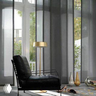 Темные полупрозрачные японские шторы на панорамных окнах; интерьер с кожаным креслом и напольной лампой создает камерную атмосферу.
