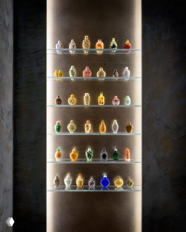 Ниша с подсвеченной полкой, на которой аккуратно выставлены маленькие разноцветные скляночки — пример организованной коллекции в интерьере.