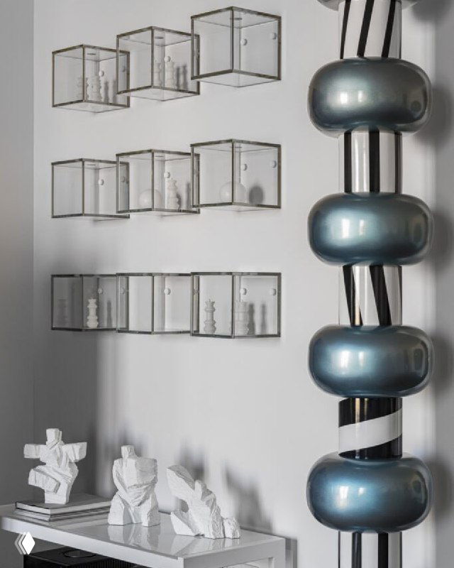 Стеклянные кубы на стене с миниатюрными фигурками и декоративными объектами — вариант презентации коллекции в современном интерьере.