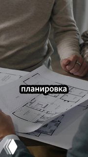 Руки держат распечатанные планы квартиры и чертежи на столе — рабочая сцена обсуждения планировки вторичного жилья для пары.