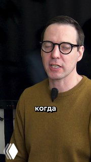 Крупный план мужчины в очках с петличным микрофоном на тёмном фоне; кадр из видеообзора жилых комплексов рядом с лицеем №130, видна белая надпись «когда».