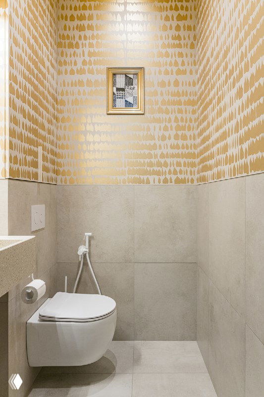 Гостевой санузел с золотой художественной росписью на верхней части стен, светлый керамогранит внизу и подвесной унитаз — общий вид пространства.