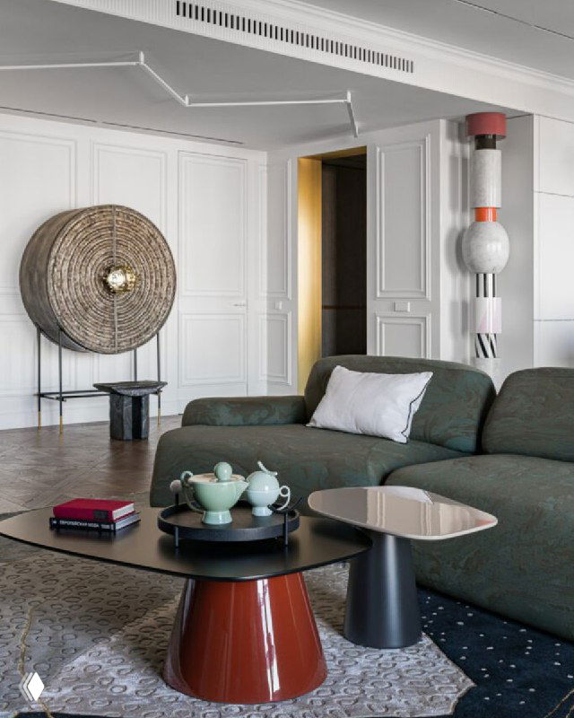 Гостиная с зелёным диваном и декоративными предметами; видно аккуратный дверной проём и интерьерные столики рядом.