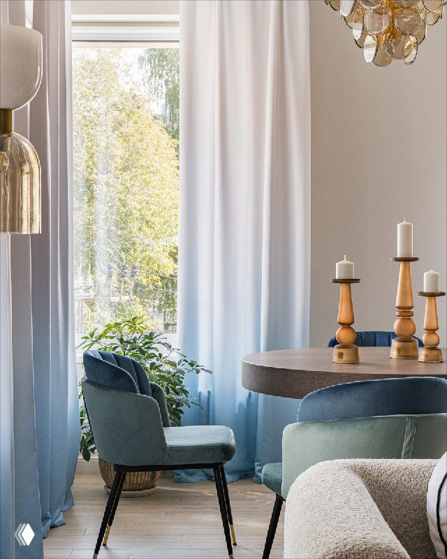 Угол кухни со синими креслами, растением у окна и овальным столом; светлые занавески и отражения придают глубину интерьеру.