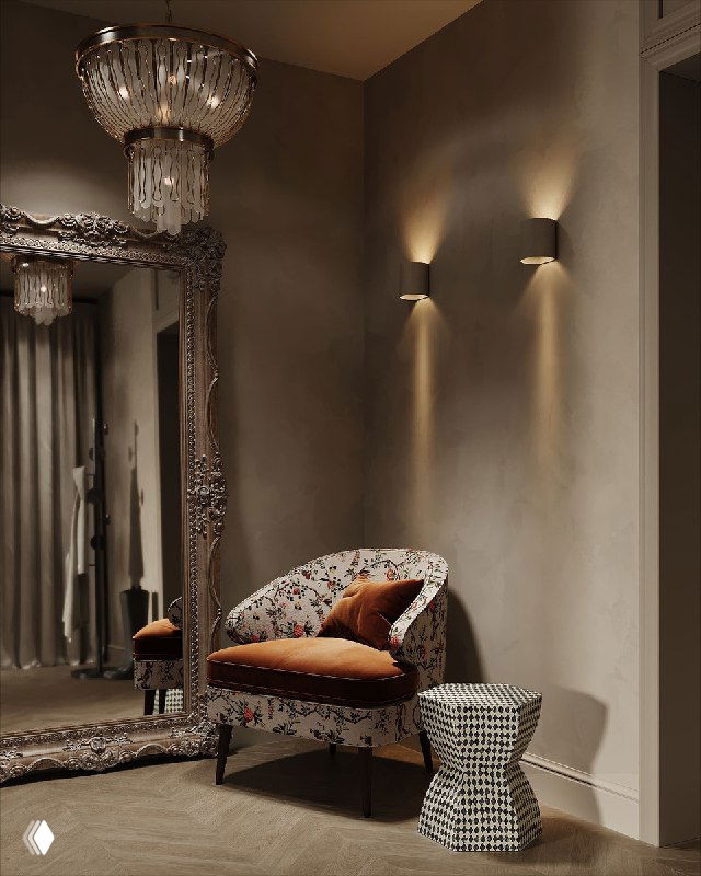 Высокое украшенное зеркало в тяжелой резной раме, отражение мягкого кресла и люстры в уютном коридоре или гардеробной зоне.