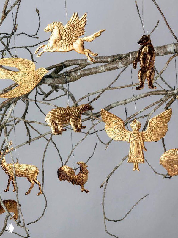 Золотые ёлочные подвески в форме животных и ангела, подвешенные на голых ветках; демонстрация украшений из фольги для мастер-класса по декору.