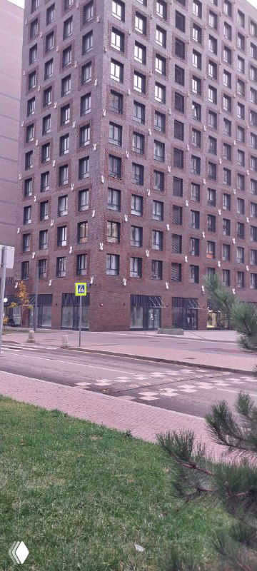 Крупный план кирпичного фасада жилого дома ЗИЛАРТ, тротуар и газон на переднем плане в городской осенней обстановке.