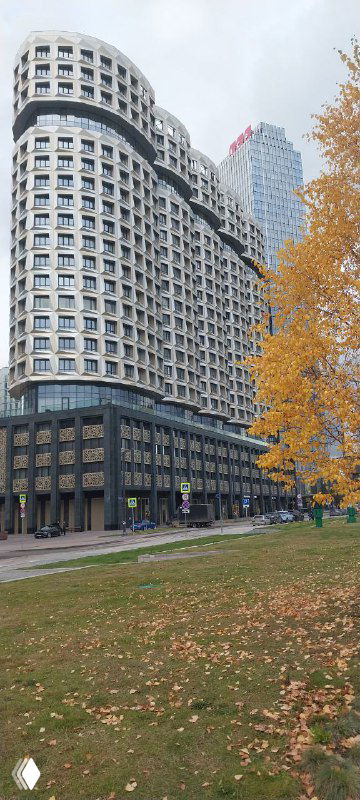 Округлые фасады и высокие дома в составе ЗИЛАРТ, осенние деревья и зелёная зона рядом с жилым комплексом.