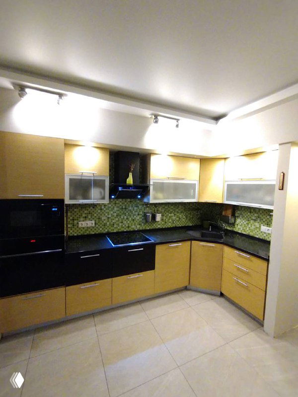 Угловая кухня после обновления фасадов и стайлинга: светлые шкафы, чёрная столешница и подсветка рабочей зоны перед съёмкой.