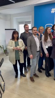 Неформальная группа участников HR‑SREDA в офисном пространстве у брендированной стены: обмен идеями, фото на память и атмосфера мероприятия.