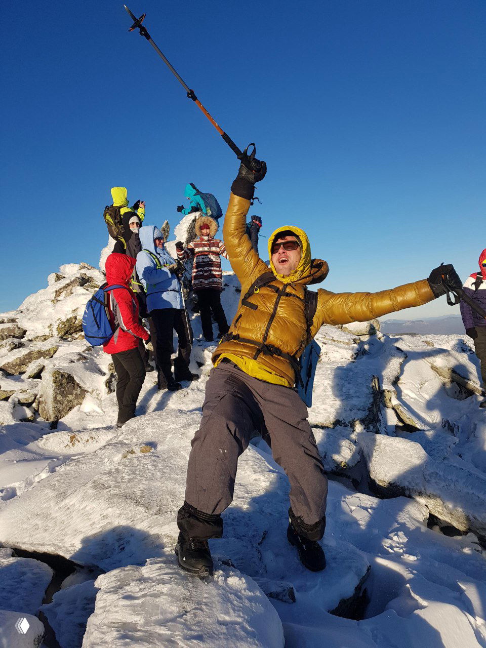 Группа туристов на заснеженной вершине Большого Иремеля: люди в тёплой экипировке радуются восхождению на фоне яркого зимнего неба.