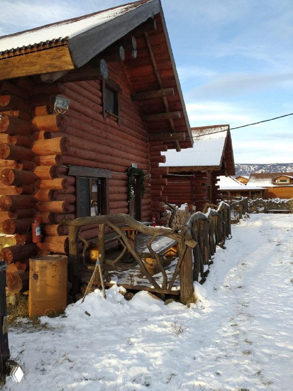 Деревянные коттеджи в заснеженном дворе: уютный базовый лагерь с тропинками и снежным покрывалом вокруг домиков.
