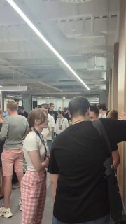 Группа людей в коридоре университета или учебного пространства: молодые люди общаются и ожидают, кадр с мероприятия или перерыва в обучении.
