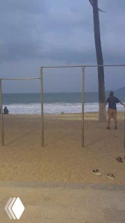 Пустой пляж с тренажёрной конструкцией и пасмурным небом; кадр отражает расслабленную атмосферу и меланхоличный пляжный пейзаж.