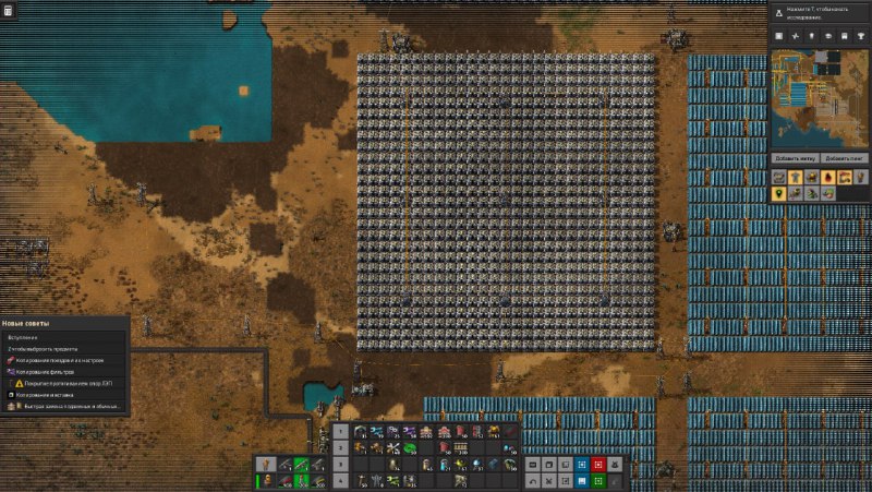 Скриншот игры Factorio: вид сверху на плотную сетку производственных построек и конвейеров, интерфейс справа, земля и вода.