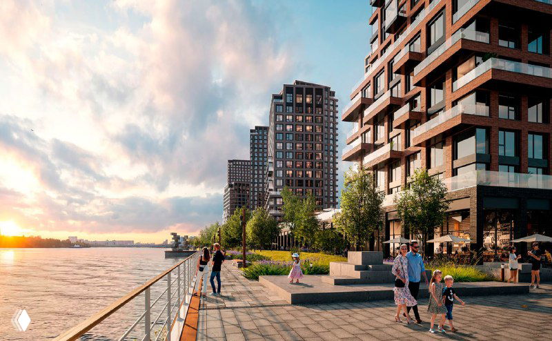 Благоустроенная набережная с прогулочной зоной, людьми, террасами кафе и видом на ряд современных жилых корпусов у воды.