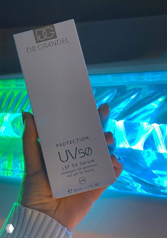 Рука держит коробку Protection UV50 LSF 50 Serum от Dr. Grandel на фоне открытой солярной лампы с голубыми неоновыми лучами.