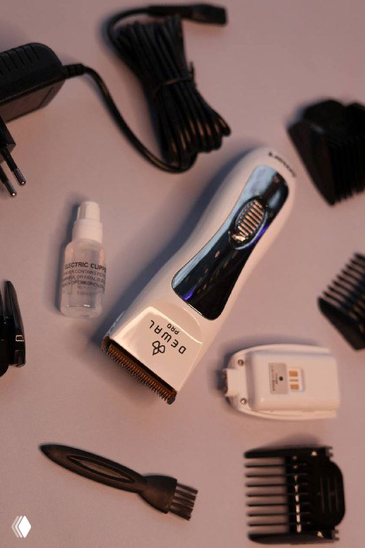 Вид сверху: машинка DEWAL PRO SMART в белом корпусе, зарядное устройство, флакон масла и несколько насадок на розовом фоне.