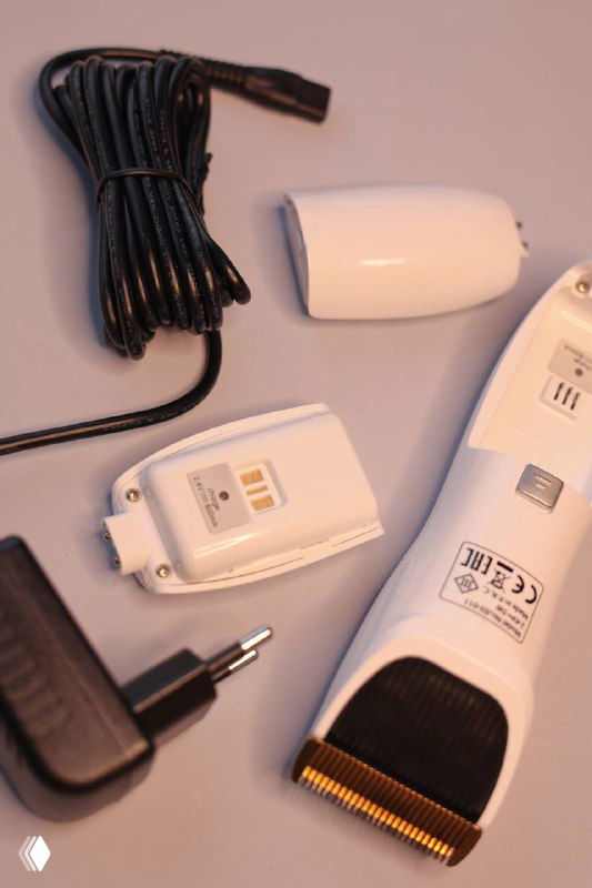 Детали комплекта: зарядное устройство и сменные элементы машинки DEWAL PRO SMART крупным планом, видны контакты зарядки.