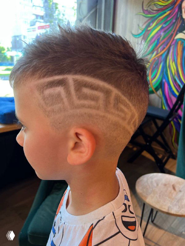 Другой боковой вид детской стрижки с декоративным рисунком; видно филировку и аккуратную детальную работу мастера в салоне.