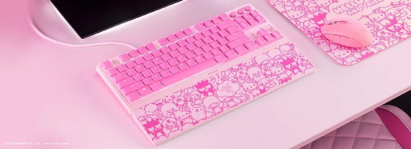 Розовая клавиатура с декоративным рисунком Hello Kitty и соответствующий коврик на столе, показаны элементы коллаборационного набора Razer.