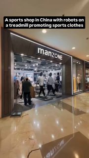 Фасад спортивного магазина в торговом центре с вывеской «manzone», у входа расположены беговые дорожки с роботами и наблюдающими покупателями.
