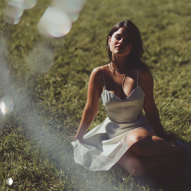 Портрет женщины, сидящей на траве в платье при мягком естественном свете и красивом боке, пример портретной фотореалистики и композиции.