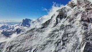 Панорамное аэрофото заснеженного склона и горной гряды, снятое дроном с большой высоты над ледяным рельефом.