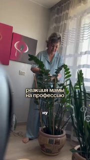 Женщина в домашней обстановке ухаживает за растениями у окна; на фото видна надпись «реакция мамы на профессию».