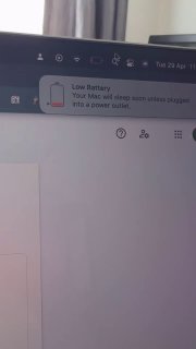 Изображение экрана MacBook: уведомление «Low Battery» в правом верхнем углу, видна часть рабочего стола и панели меню.