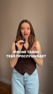 Женщина в комнате держит маленькое устройство в руке, на фото наложен текст «iPhone тайно тебя прослушивает» — иллюстрация темы приватности.