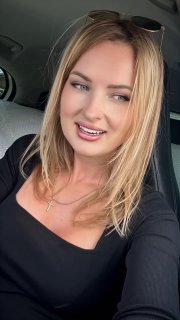 Крупный план вертикального видео: блондинка в салоне автомобиля, улыбка и разговор с камерой, модельный портрет в движении.