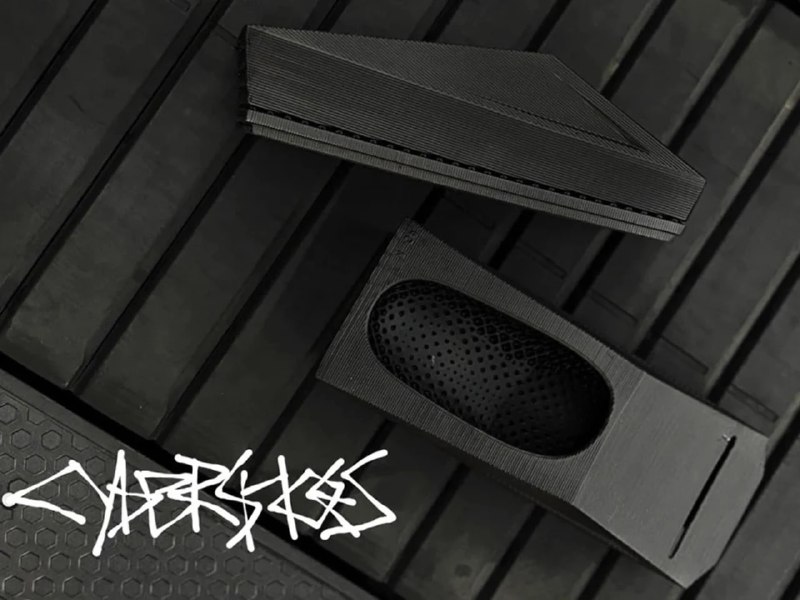 Несколько частей прототипа CyberShoes на темной поверхности: видны верхняя и нижняя части с внутренней сеткой и фон с логотипом.