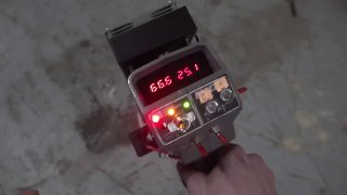 Крупный план самодельного лазерного устройства в руке оператора с цифровым дисплеем, индикаторами и управляющими элементами, демонстрирующий опасный прибор.