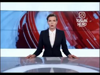 Ведущая новостей в студии: женщина в строгом костюме за стеклянным столом на фоне видеостены с графикой.