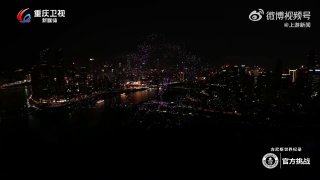 Ночной панорамный вид на город и освещённую набережную, кадр из видеозаписи масштабного шоу дронов над бухтой с огнями
