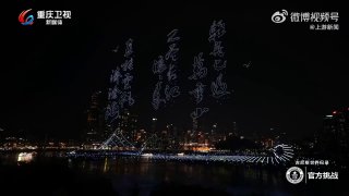 Силуэты дронов в форме светящихся китайских иероглифов над ночной водой, видна набережная и городской горизонт — кадр из шоу дронов
